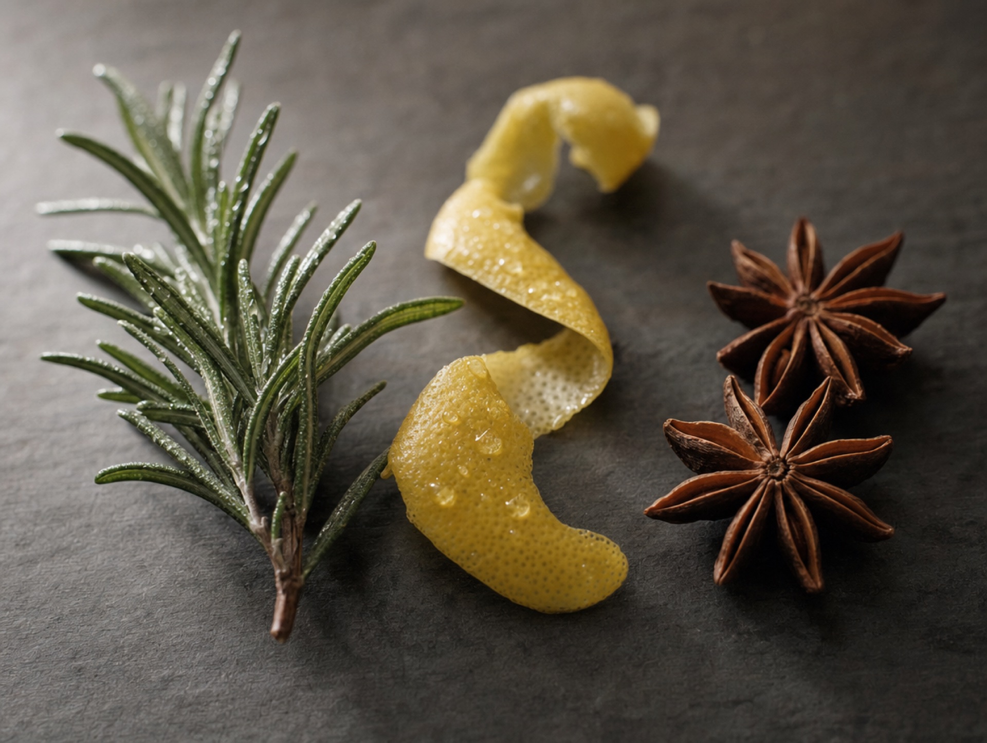 Drei Cocktail-Garnituren in Reihe: Rosmarin, Zitronenzeste, Sternanis