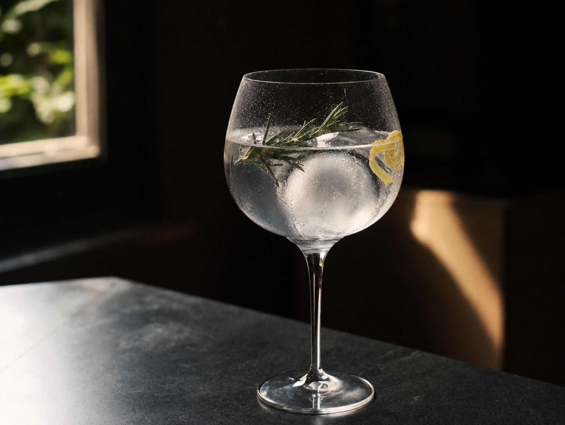 Copa-Glas in Detail mit Gin Tonic, Rosmarinzweig und Eiskugel