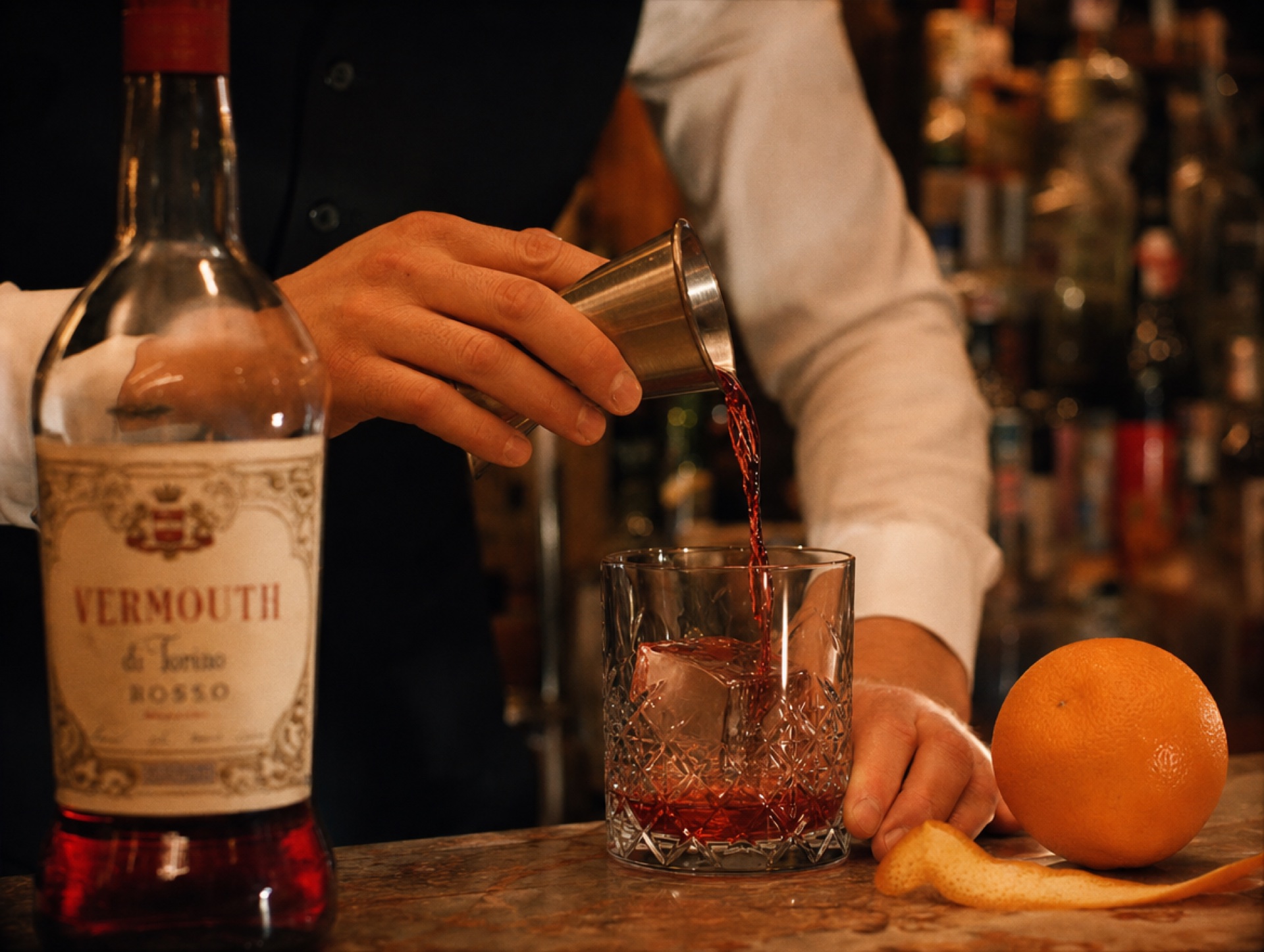 Hände eines Bartenders gießen Campari für einen Negroni