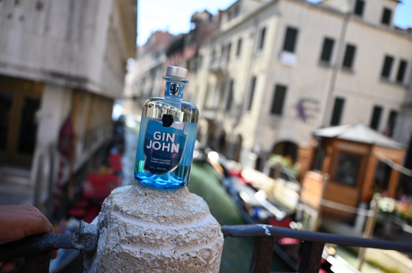 Gin John auf Brückengeländer mit Canal und Gondeln im Hintergrund